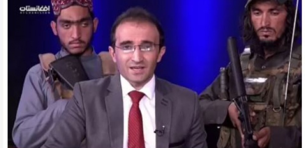 Un présentateur afghan présente le journal entouré de talibans armés